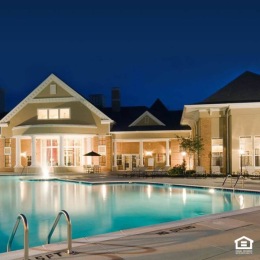 a courtyard with a swimming pool and a large building with lights in the background